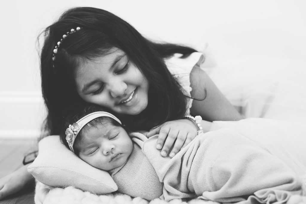 sisters snuggling during lifestyle newborn session