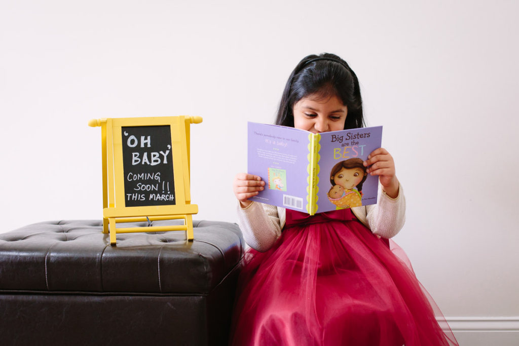 little girl reading book about being a big sister