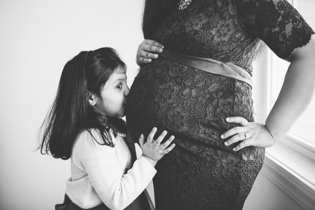 big sister kisses moms pregnant belly