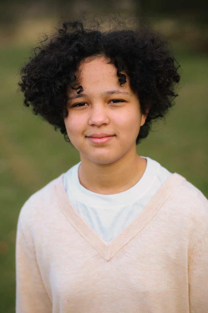 Teenage girl with black curly hair and tan sweater Clifton Park NY