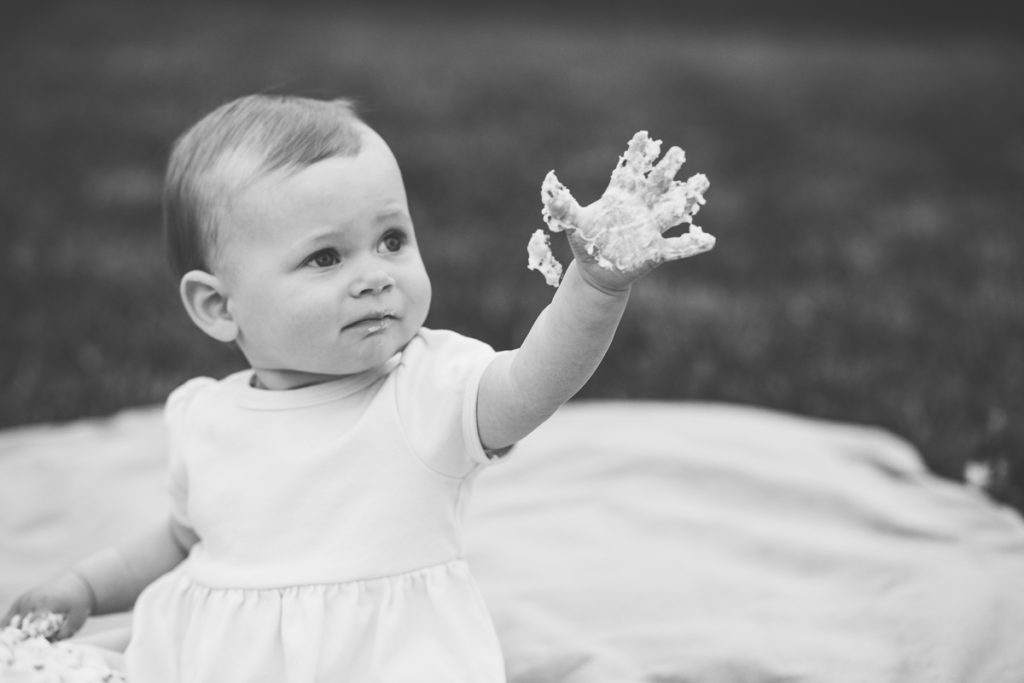 hand covered in frosting after a cake smash albany ny baby photography