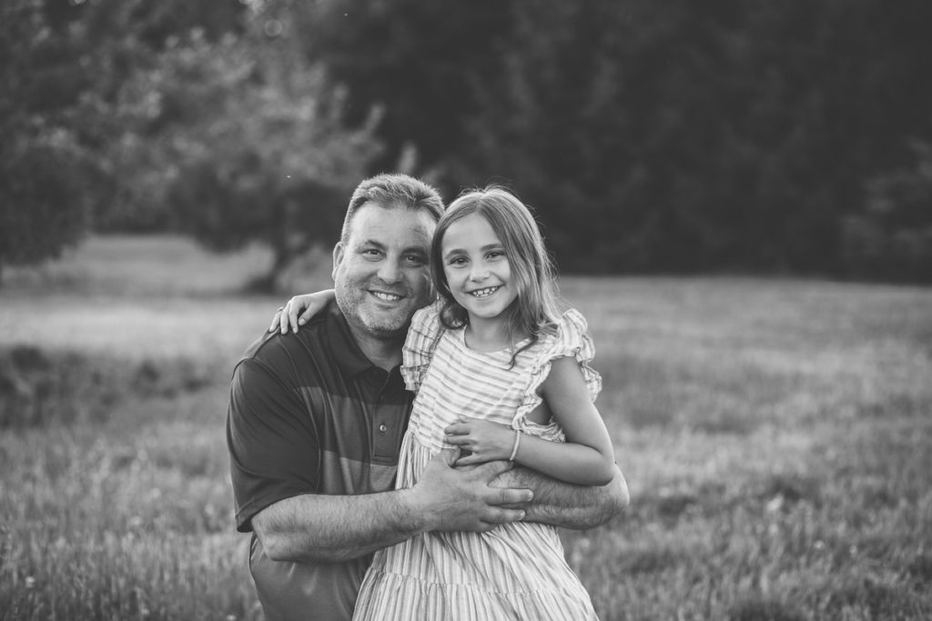 dad snuggling daughter in pink stripped dress