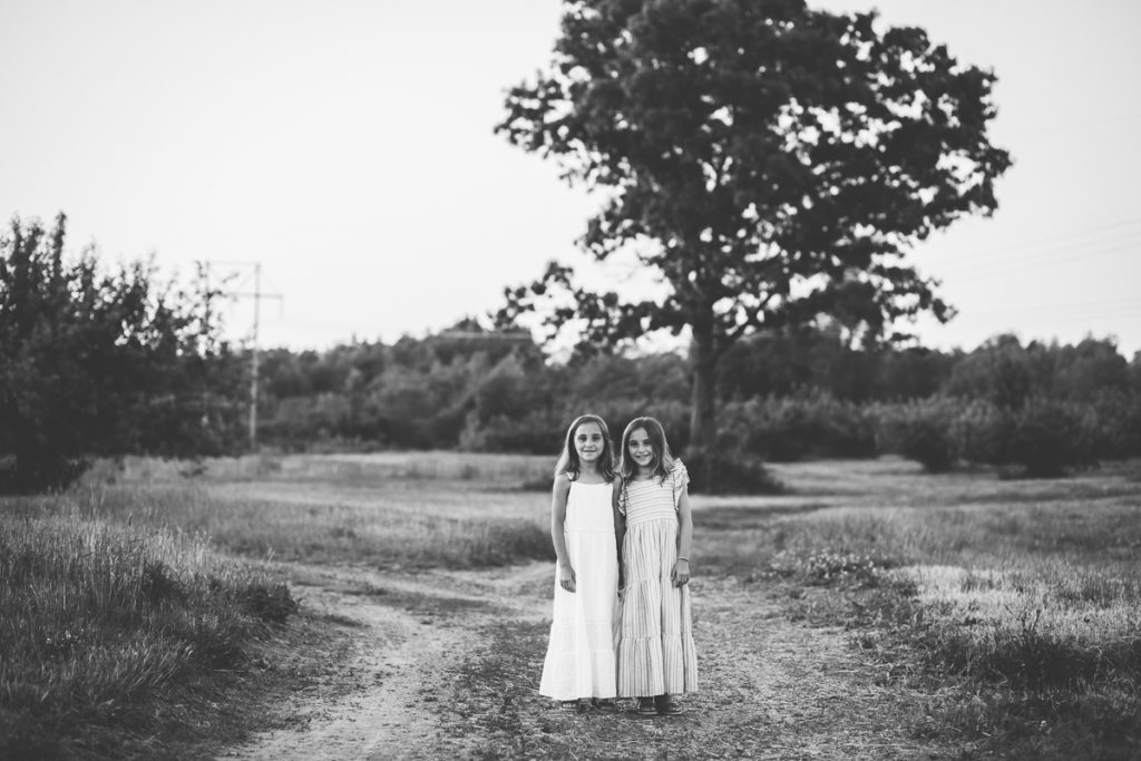 twin girls standing in an apple orchard