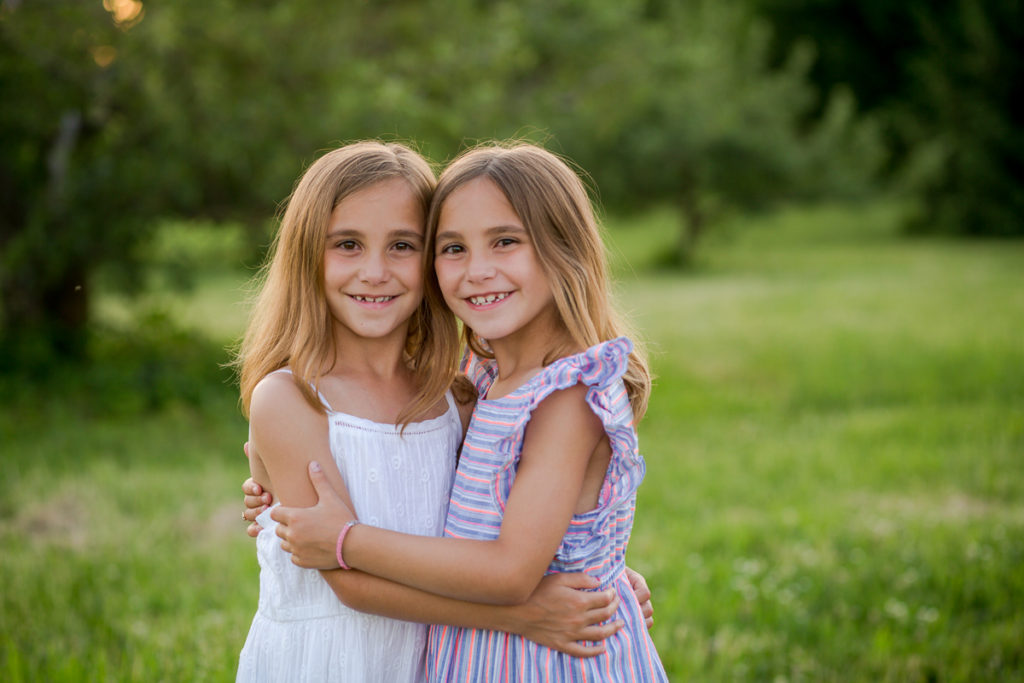 twin girls standing close hugging
