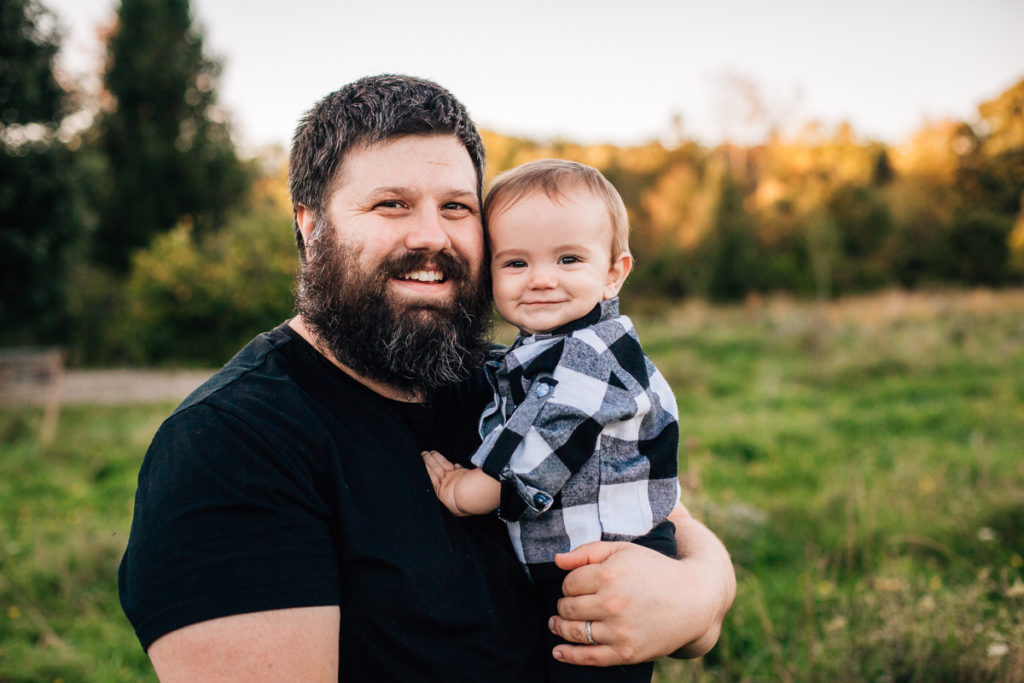 dad holding baby boy wearing black and white plaid