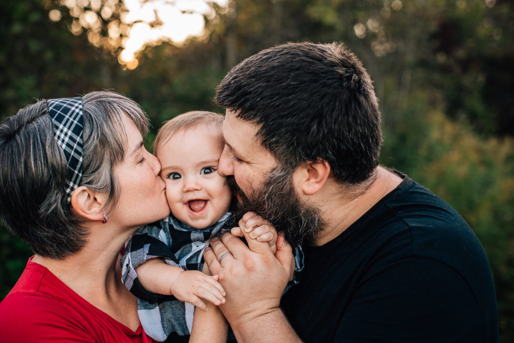 mom and dad kissing baby boy on the cheeks