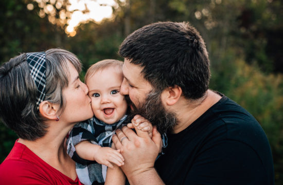 mom and dad kissing baby boy on the cheeks