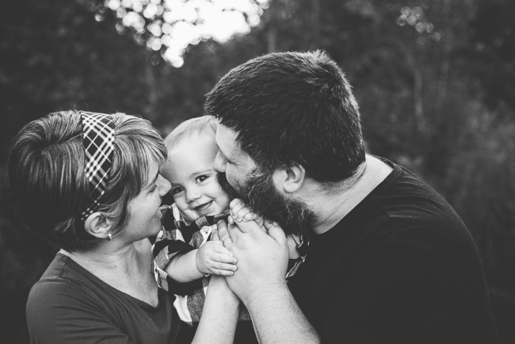 black and white picture of mom and dad snuggling baby