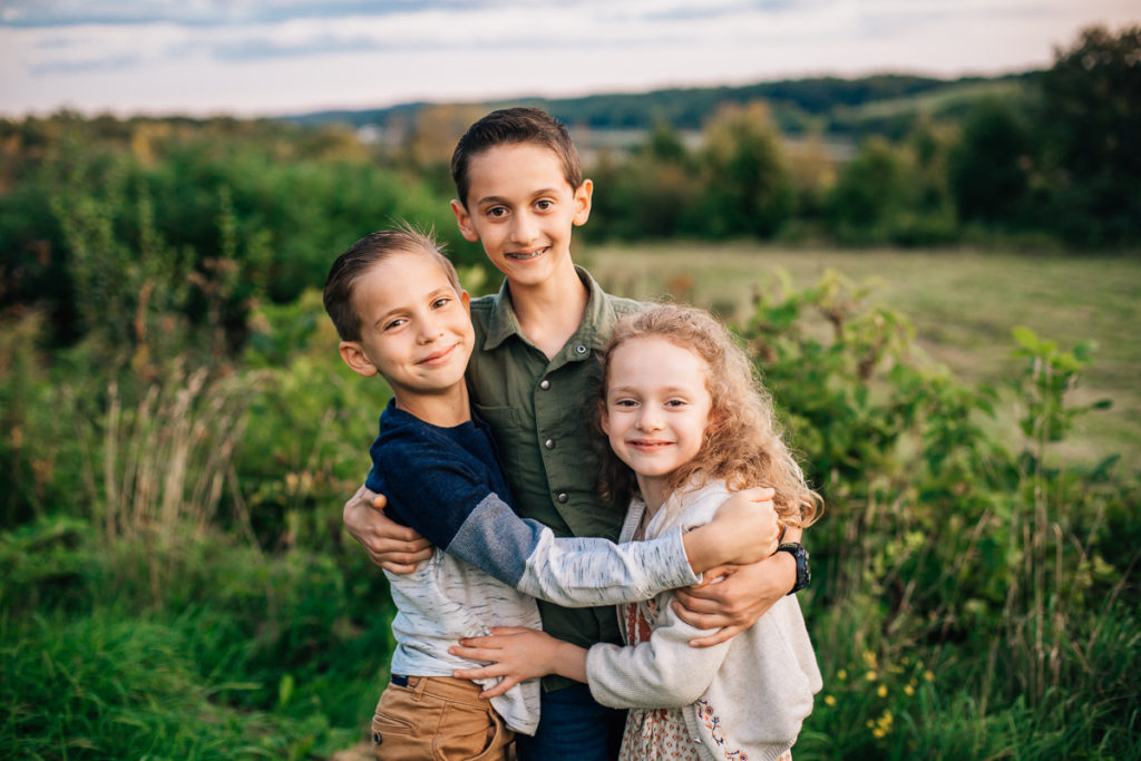 two brothers and a sister hugging