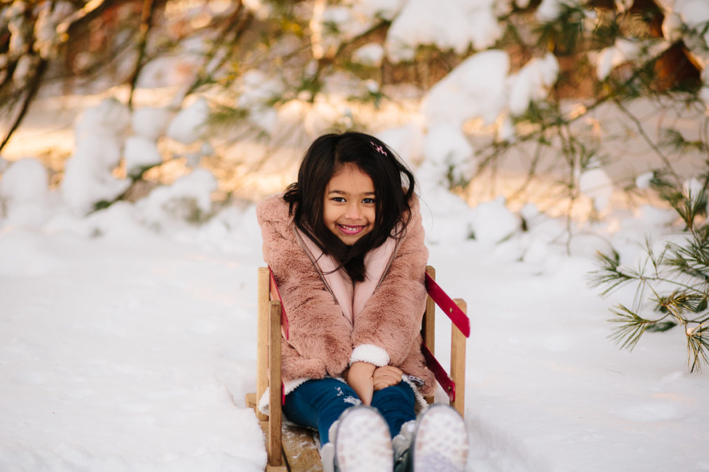 little girl sitting on sled in snow Clifton Park NY